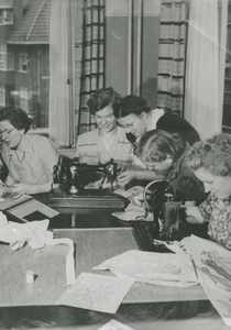 876910 Afbeelding van enkele jonge vrouwen die een naailes volgen tijdens hun opleiding tot sociaal werkster bij de ...
